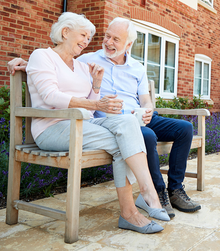 An elderly couple sitting on an outdoor bench